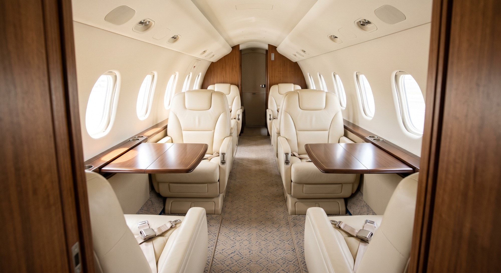 Illustration: the cabin of a light business jet, cream leather seats and wood tables