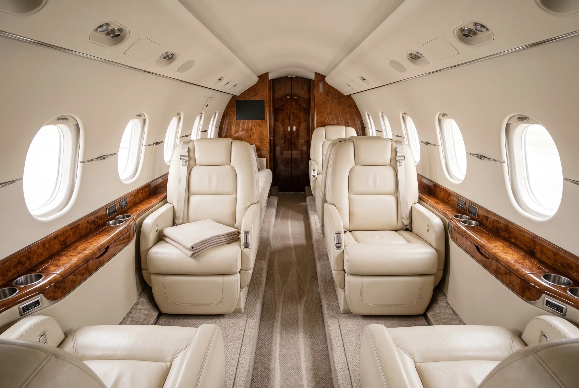 Illustration: a business jet cabin with cream leather seats, walnut side ledges and oval windows