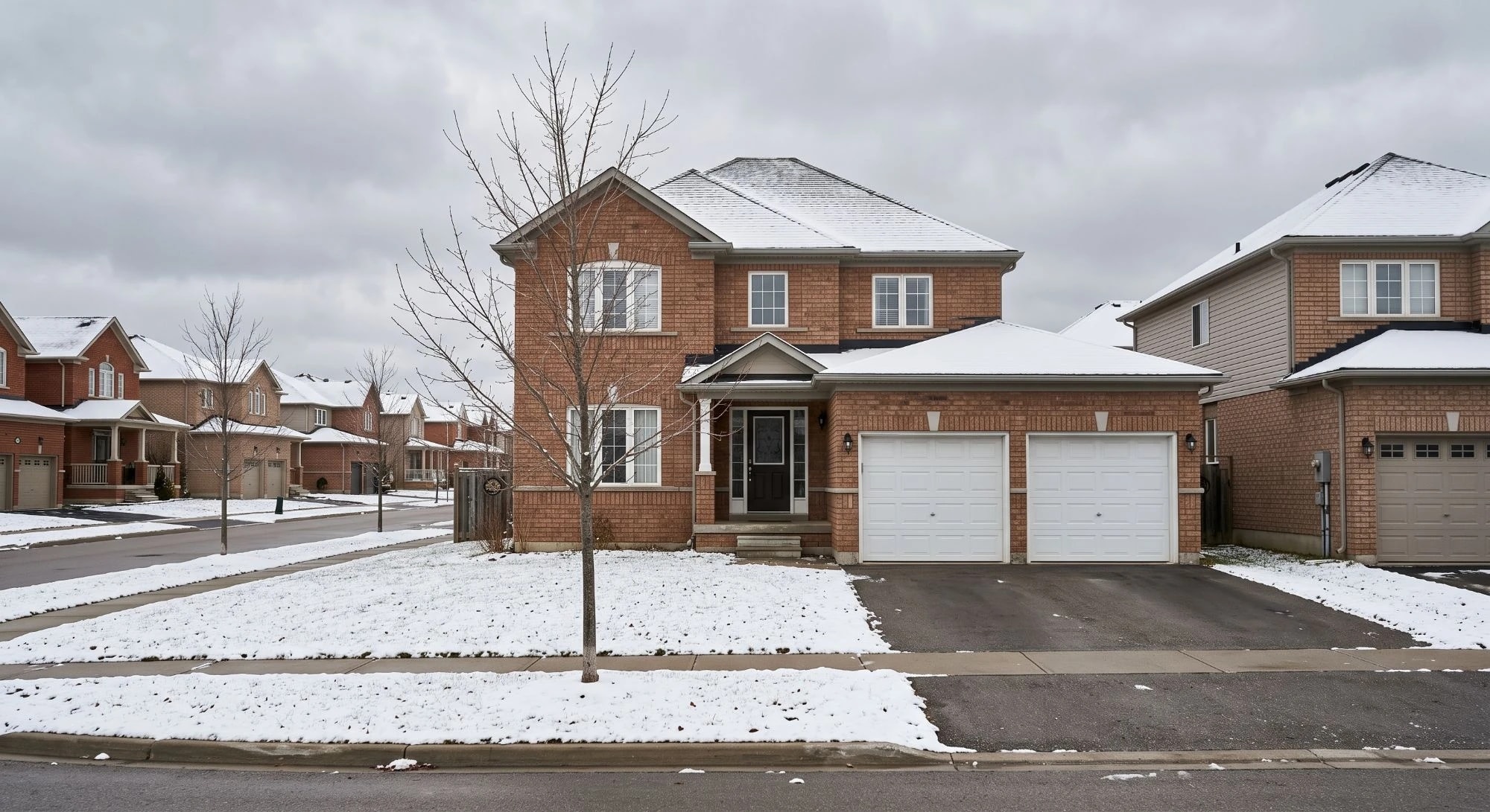 Illustration: a two-story brick house with a double garage after a light snowfall