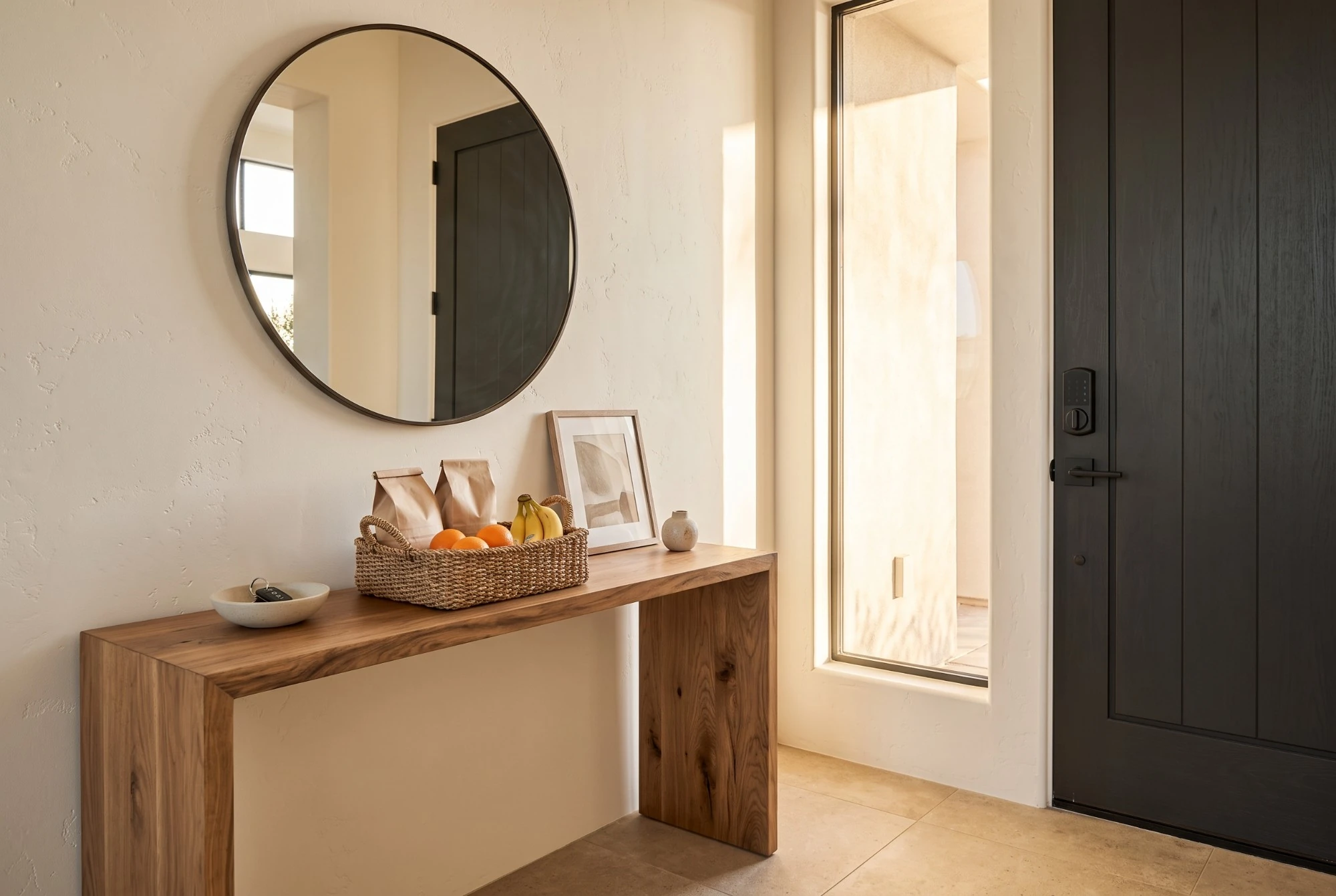Illustration: a rental entryway with a wooden console, a welcome basket, a round mirror and a black smart lock on the door