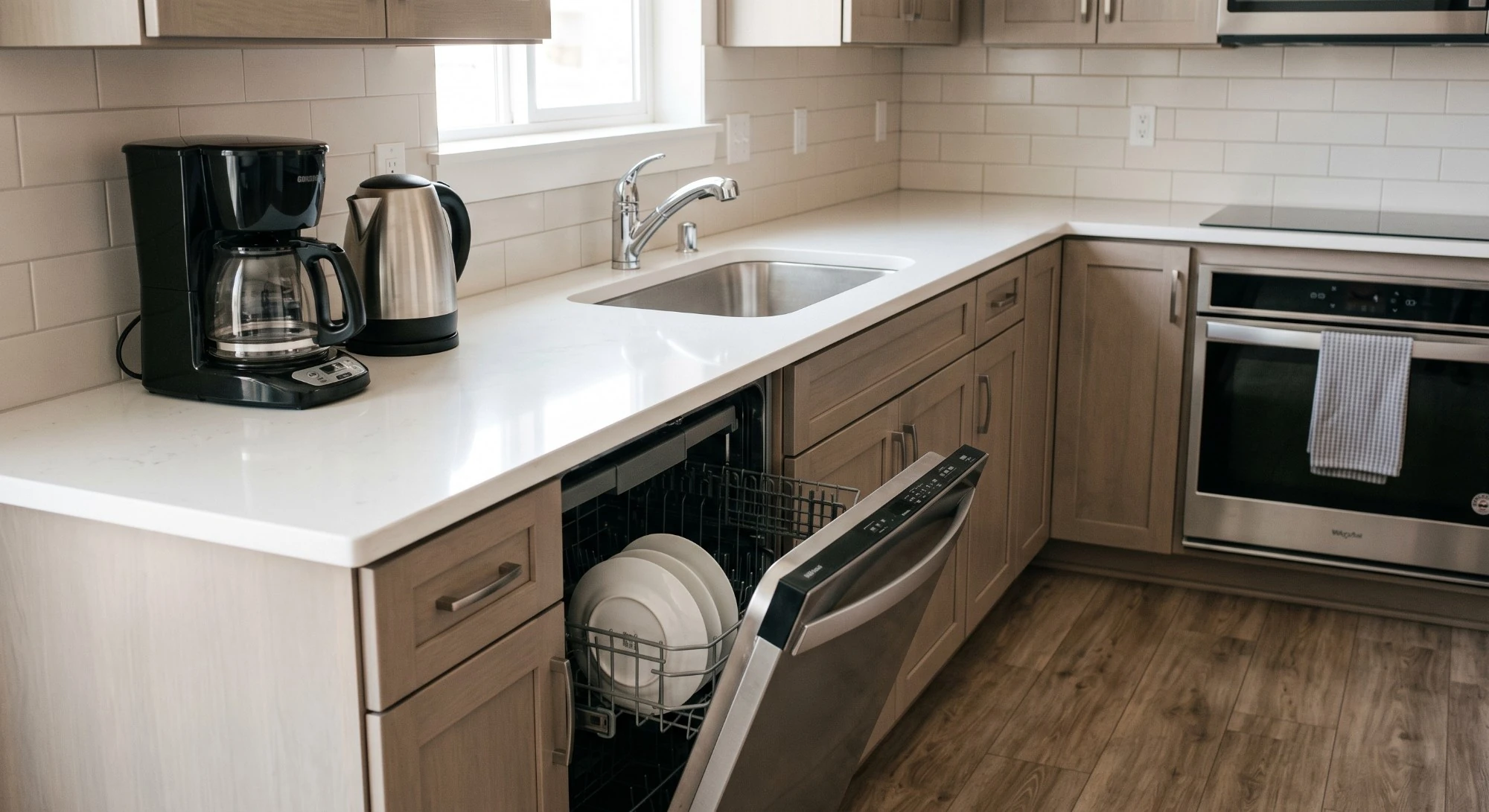 Illustration: a kitchen counter with a coffee maker, a kettle and an open dishwasher with clean plates